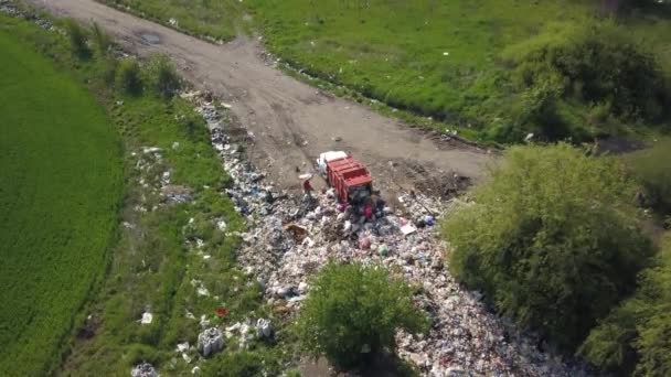 Een vuilniswagen arriveert op een natuurlijke stortplaats. Mensen dumpen afval bij de ingang. Luchtopname. — Stockvideo