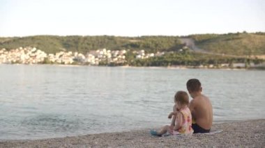Kız ve erkek sahilde oturuyor. Erkek ve küçük kız kardeş deniz kenarında dinleniyorlar. Duygular, aşk, şefkat,