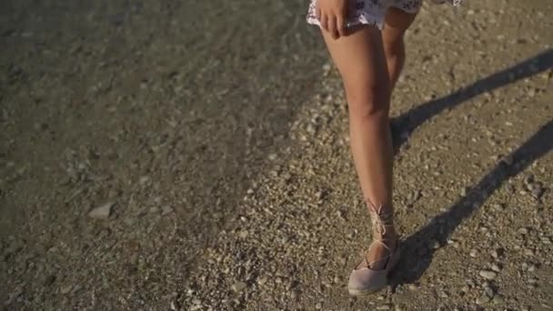 Flickan går på stranden med småsten i skor. — Stockvideo