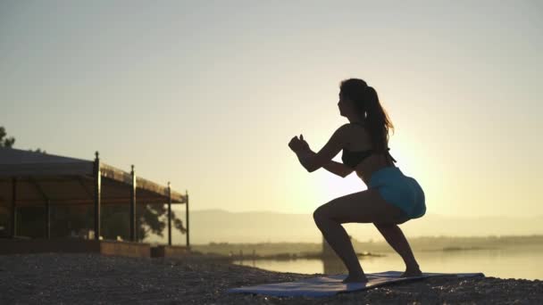 Vacker kvinna tränar på stranden. hav, soluppgång, strand, träning, slow motion — Stockvideo