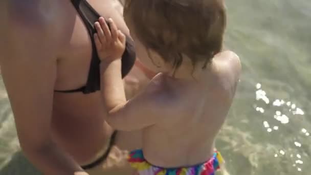 Mamá con su pequeña hija jugando en el agua. Chica 2 años salpicando en el agua. Buenos días Croacia. — Vídeo de stock