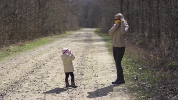 Mamá se pone una máscara protectora para bebés. Caminar en el bosque durante la cuarentena. — Vídeo de stock