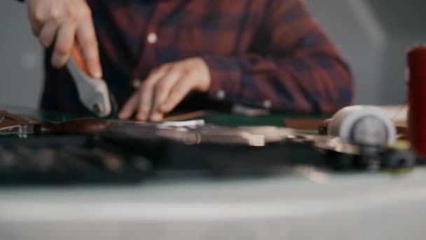 Processen att tillverka en handgjord läderplånbok. Hantverkaren skar av en läderbit. Handgjorda lädervaror. — Stockvideo