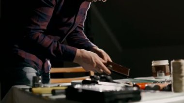 El yapımı deri cüzdan üretme işlemi. Zanaatkar titizlikle bitmiş ürünü inceler. El yapımı deri eşyalar..