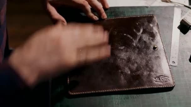 Proces produkcji skórzanego portfela ręcznie robionego. Rzemieślnik nakłada żel zmiękczający na gotowy produkt. Wyroby skórzane ręcznie. — Wideo stockowe