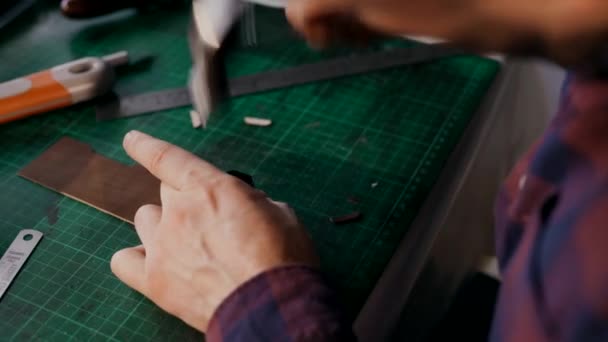 The process of manufacturing a leather wallet handmade. The craftsman cut off a piece of leather. Handmade leather goods. — Stock Video