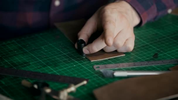 Le processus de fabrication d'un portefeuille en cuir fait main. L'artisan a coupé un morceau de cuir. Maroquinerie artisanale. — Video