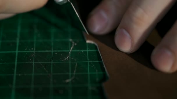 Il processo di produzione di un portafoglio in pelle fatto a mano. L'artigiano ha tagliato un pezzo di pelle. Articoli in pelle fatti a mano. Macro. — Video Stock