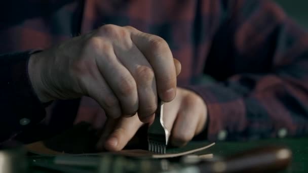 Le processus de fabrication d'un portefeuille en cuir fait main. L'artisan perce des trous pour clignoter. Maroquinerie artisanale. Macro. — Video