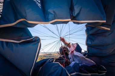 Siyah saçlı Latin adam uçtuktan sonra paraşütünden yelkeni kaldırıyor.