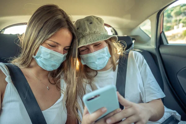 Ragazze Con Maschere Che Guardano Smartphone Sui Sedili Posteriori Una Fotografia Stock