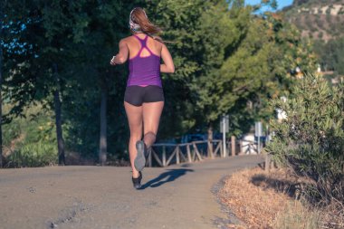 Mor kolsuz bluzuyla parkta koşan genç Latin kız.