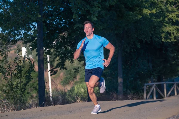 Mavi gömlekli genç adam ve mor gömlekli genç kadın arka planda ağaçlarla parkın içinde koşuyorlar.