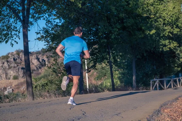 Mavi gömlekli genç adam ve mor gömlekli genç kadın arka planda ağaçlarla parkın içinde koşuyorlar.