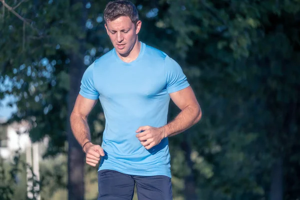 Mavi gömlekli genç adam ve mor gömlekli genç kadın arka planda ağaçlarla parkın içinde koşuyorlar.