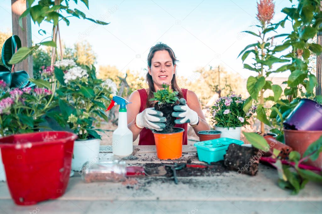 Young latin woman wearing a red dress and gloves surrounded by plants and pots on a wooden table