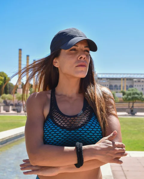 Standing sports trainer wearing blue sportswear and black cap posing in the park