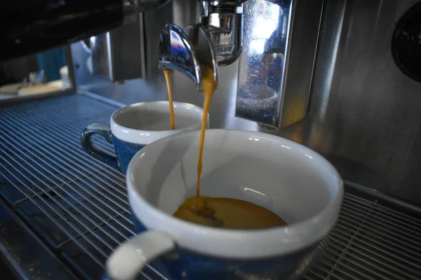 Preparing a double coffee in blue cups with a coffee machine