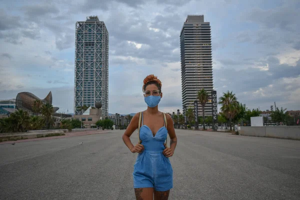 Young woman walking through the empty city of Barcelona wearing a face mask