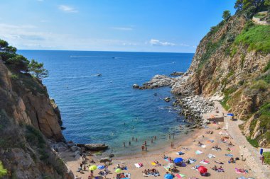 Girona, İspanya, 09 / 09 / 2020: Turkuaz sulu Cala es Codolar, yaz boyunca güneşlenen insanlarla birlikte arkadan fotoğraflandı.