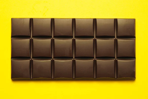 A bar of dark dark chocolate on a yellow background