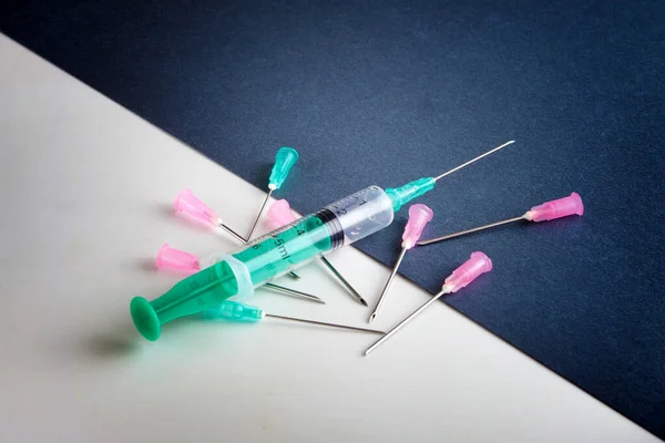 Syringe and different syringe needles on a black and white surface