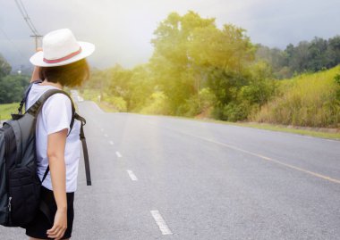 Sırt çantası taşıyan bir kız yolda duruyor.