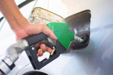 Yakından, benzin istasyonunda yakıt ikmali yapan araçlar. Çalışanlar yakıt ikmali yapmak ve benzini benzin istasyonunda doldurmak için el ele tutuşuyorlar. Benzin istasyonunda yakıt ikmali yapan araba..