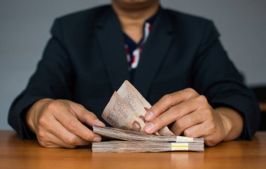 Bir adamın eli binlerce baht para sayar. Tayland parası.