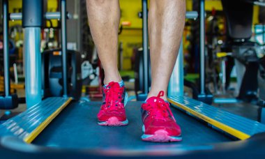 Erkekler yavaşça yürüyor, koşu bandında egzersiz yapıyorlar.