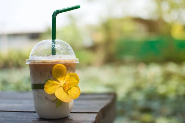 Iced coffee, plastic cup on a wooden table, morning sunlight