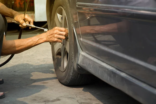 Arabasının lastiklerini şişiren bir adamın yakın çekimi.