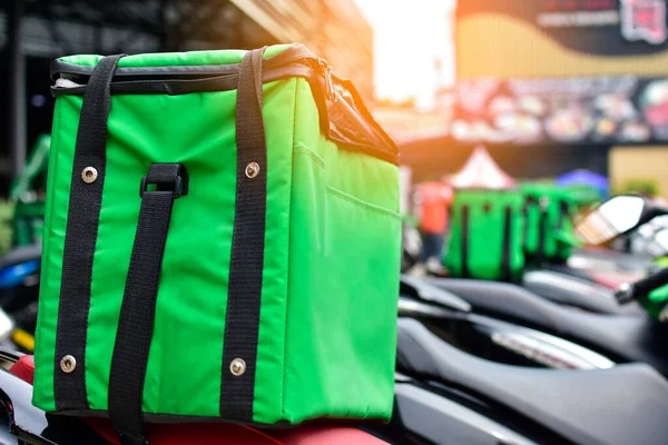 Yemek dağıtım elemanlarının motosikletindeki yeşil çanta müşterilere çevrimiçi yemek siparişi vermek için bekliyor..