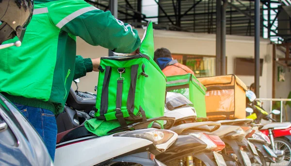 Yemek teslimatı sürücüsü ürünü çevrimiçi siparişe göre müşteriye teslim etmek için hazırlıyor. Salgın hastalıkların etkisi