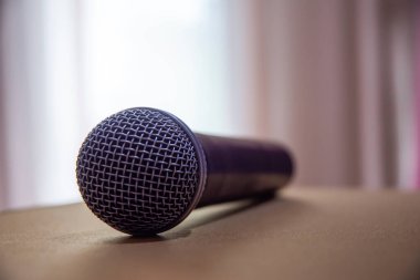 Arkadaki masada mikrofon var, perdede ışık parlıyor..