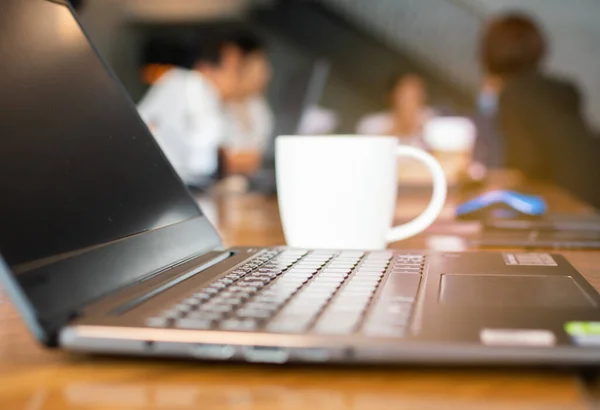 Masalardaki bilgisayarların ve toplantılarda oturan insanların bulanık resimleri.