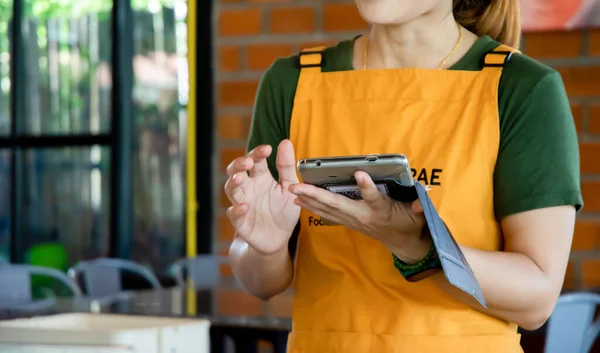Kadın çalışanlar restoranlarda müşterilerden sipariş almak için tablet kullanıyorlar: Restoran sektöründe modern kuyruklar