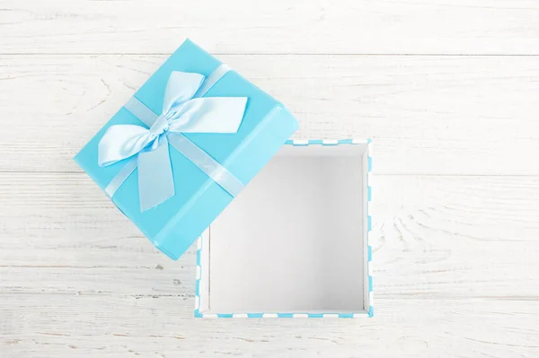 Blue gift open box with ribbon on white wooden background. Father\'s day concept