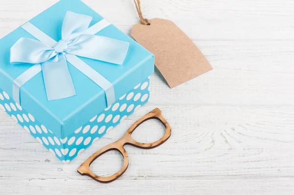 Blue gift box with ribbon on white wooden background. Father\'s day concept with copy space