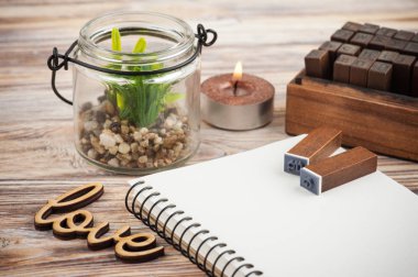 Boş defter, ahşap işareti aşk, scrapbooking DIY dekor, alphabeth pullar, sulu ve ahşap arka plan üzerinde mum yaktı