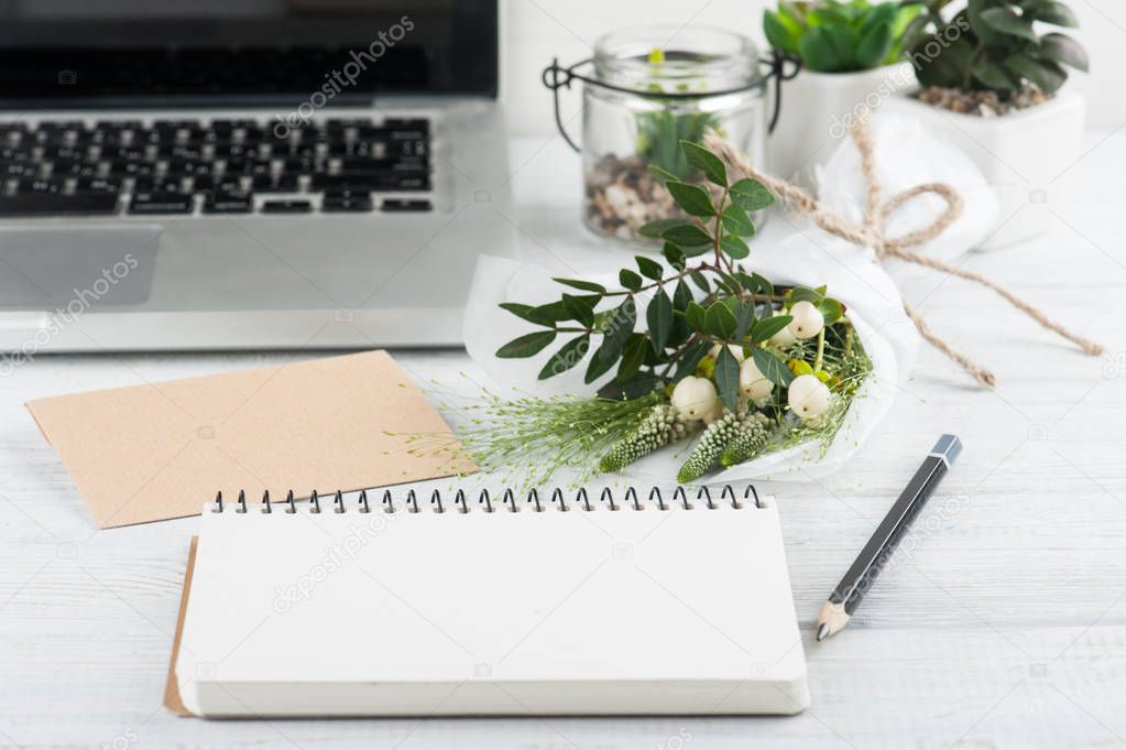Bouquet, notebook, craft envelope, laptop on wooden background. Concept for workshop or celebration. Shabby chic style
