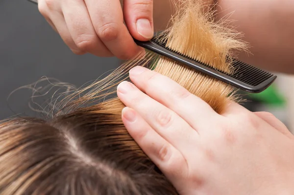 Combing blond hair with brush, closeup