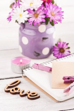 Boş defter, yanan mum ve ahşap arka plan üzerinde pembe mor Bahçe çiçek