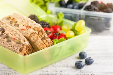 Vejetaryen sandviç ve çilek yemek kutusu ve meyve ve sebze ahşap tablo