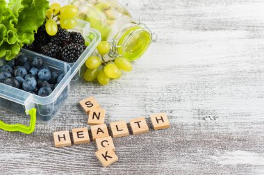 Word Snack ve öğle yemeği kutusu ahşap masa üzerinde meyveleri
