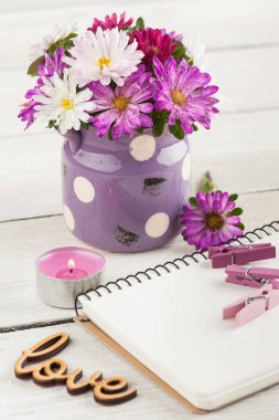 Boş defter, yanan mum ve ahşap arka plan üzerinde pembe mor Bahçe çiçek