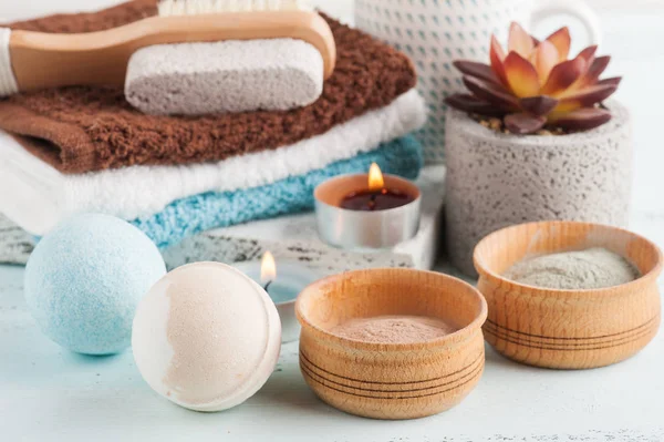 Bath bombs and moroccan clay powder, spa composition with brush and lit candles on white background