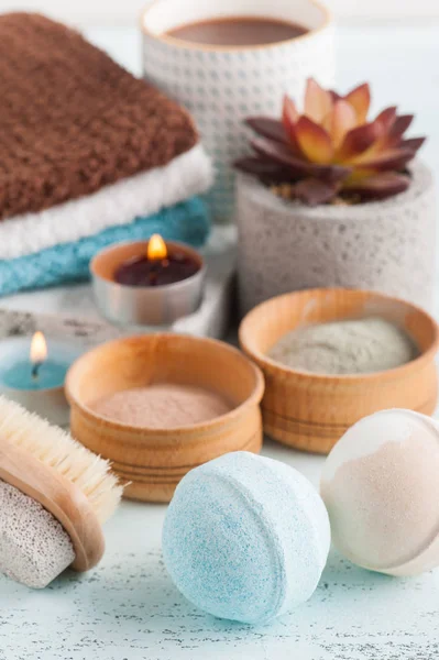 Bath bombs and moroccan clay powder, spa composition with brush and lit candles on white background
