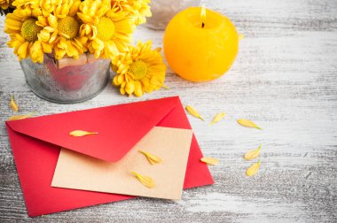 Kırmızı boş zarf ve altın sarı kasımpatı ahşap arka plan üzerinde teneke tencerede. Metin için yer kopyalayın