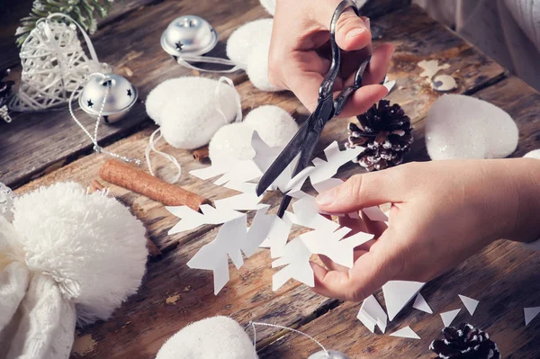 Onun resepsiyon kesme kar tanesi Noel dekorasyonu için oturan kız. Koyu ahşap arka plan ellerde closeup